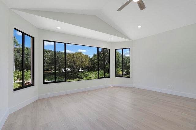 spare room with a healthy amount of sunlight, light hardwood / wood-style flooring, and vaulted ceiling