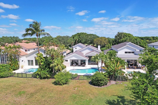 rear view of house with a patio area, a yard, and a fenced in pool