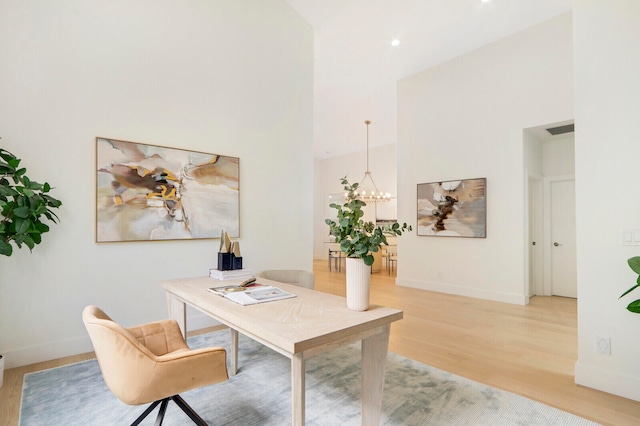 office area with high vaulted ceiling, light wood-type flooring, and a chandelier