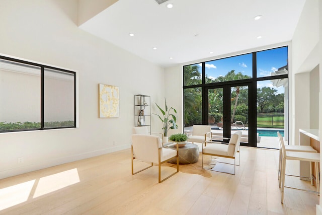 sitting room with french doors, light hardwood / wood-style flooring, and a wall of windows