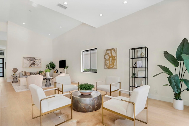 living room featuring a towering ceiling and light wood-type flooring