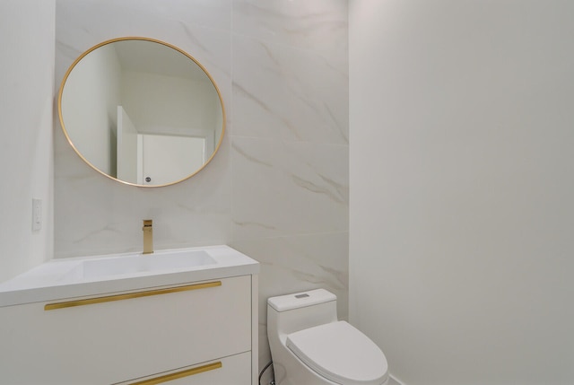 bathroom with tile walls, toilet, and vanity