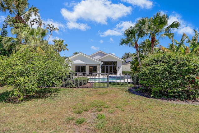 rear view of property with a fenced in pool and a yard