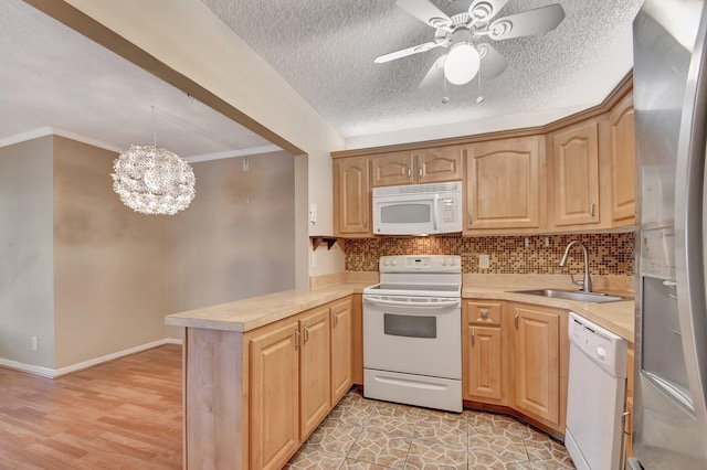 kitchen with hanging light fixtures, light hardwood / wood-style flooring, kitchen peninsula, white appliances, and light brown cabinetry