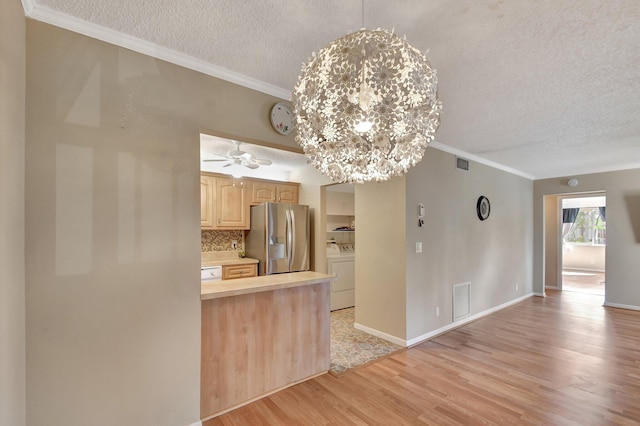 kitchen featuring light brown cabinets, light hardwood / wood-style flooring, stainless steel fridge, a textured ceiling, and washer / dryer