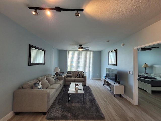 living room with light wood-type flooring, ceiling fan, and track lighting