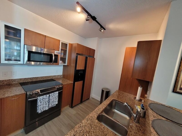 kitchen featuring fridge with ice dispenser, stone countertops, electric range, rail lighting, and sink