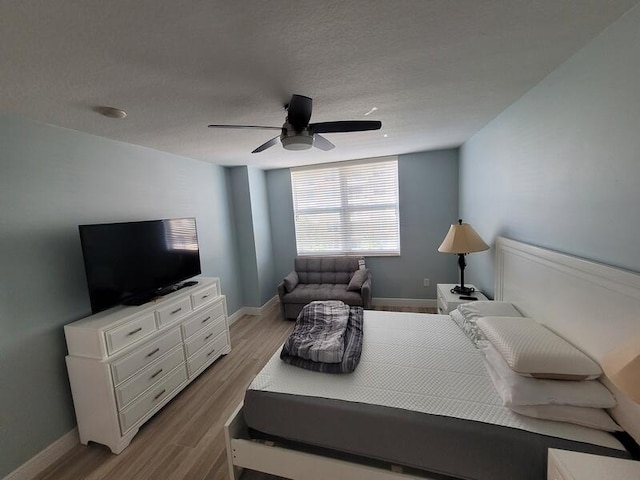 bedroom with light hardwood / wood-style floors, ceiling fan, and a textured ceiling