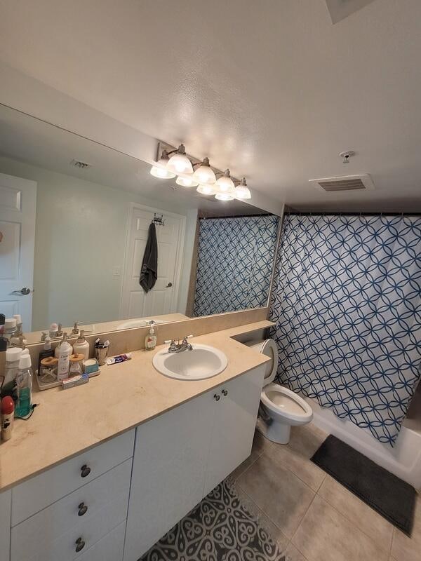 bathroom with toilet, vanity, and tile flooring