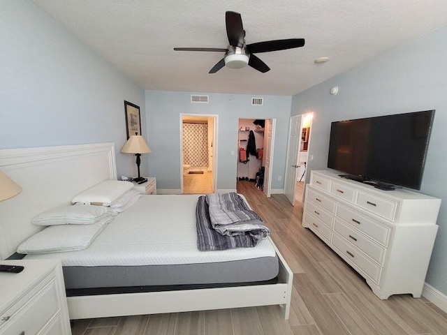 bedroom featuring ceiling fan, a closet, light wood-type flooring, and a spacious closet