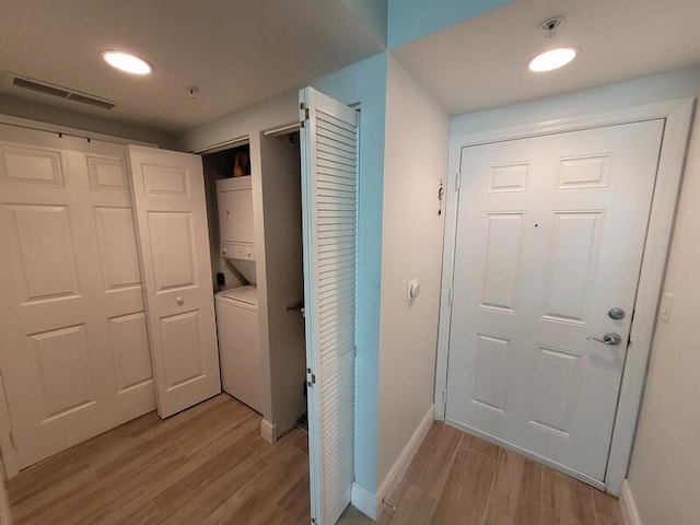 doorway to outside featuring stacked washer / dryer and light hardwood / wood-style flooring