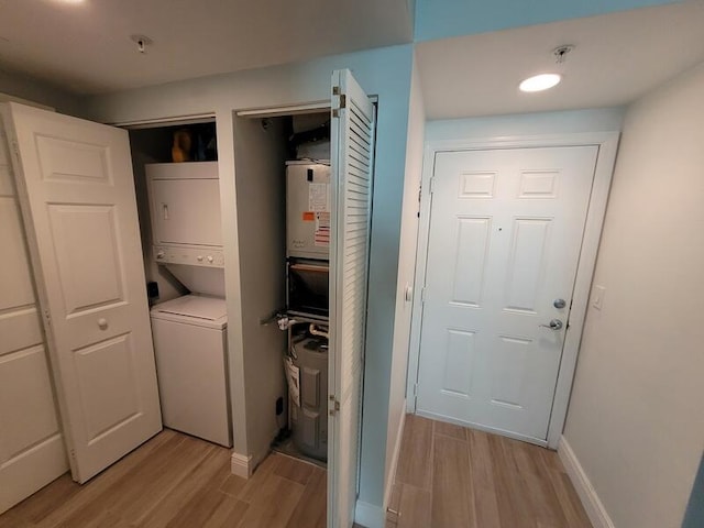 laundry room featuring stacked washer / dryer and light wood-type flooring