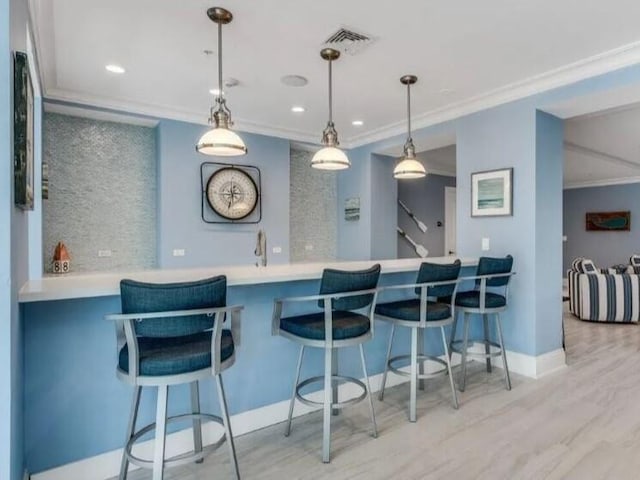 kitchen featuring hanging light fixtures, light hardwood / wood-style flooring, kitchen peninsula, and crown molding