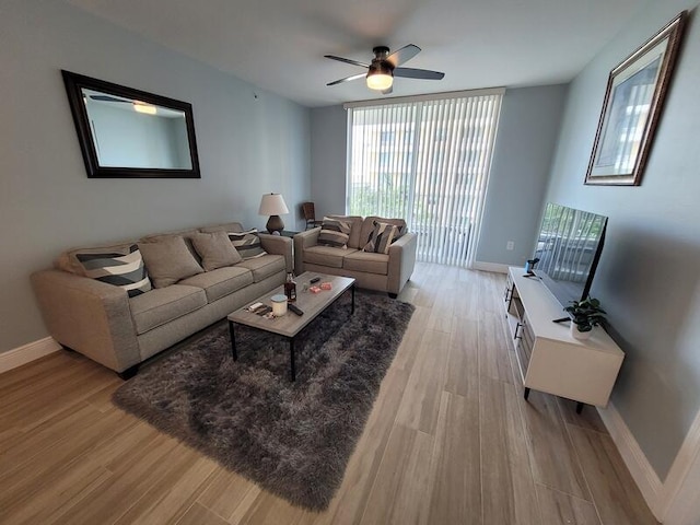 living room featuring floor to ceiling windows, ceiling fan, and light wood-type flooring