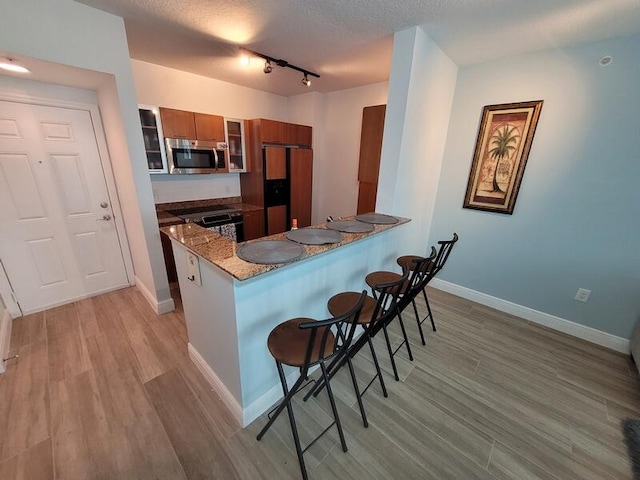 kitchen with a kitchen bar, track lighting, stove, and kitchen peninsula