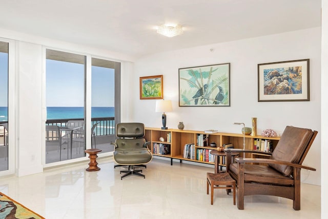 living area featuring a water view, a wall of windows, and light tile floors