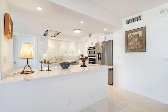 kitchen featuring light tile floors, light stone countertops, appliances with stainless steel finishes, white cabinetry, and sink