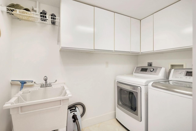 clothes washing area featuring cabinets, sink, light tile floors, electric dryer hookup, and washing machine and clothes dryer