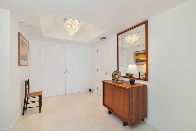 tiled foyer featuring a chandelier and a raised ceiling