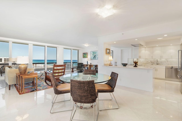 tiled dining space featuring a water view, expansive windows, and sink