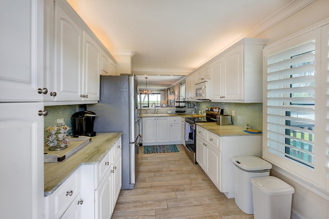 kitchen featuring white cabinets, tasteful backsplash, light wood-type flooring, hanging light fixtures, and stainless steel appliances