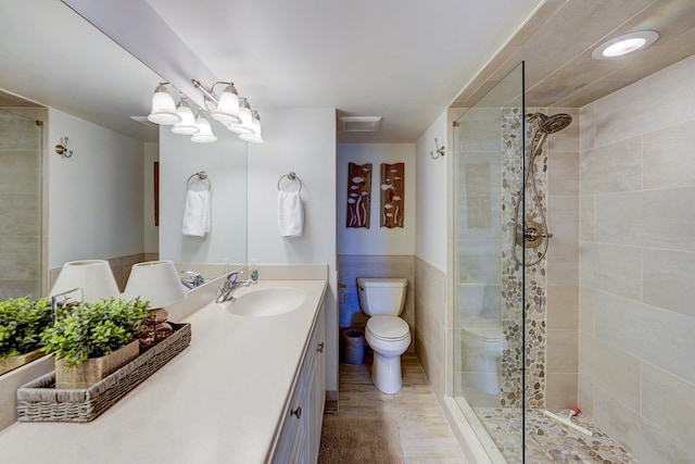 bathroom featuring a shower with shower door, vanity, and toilet