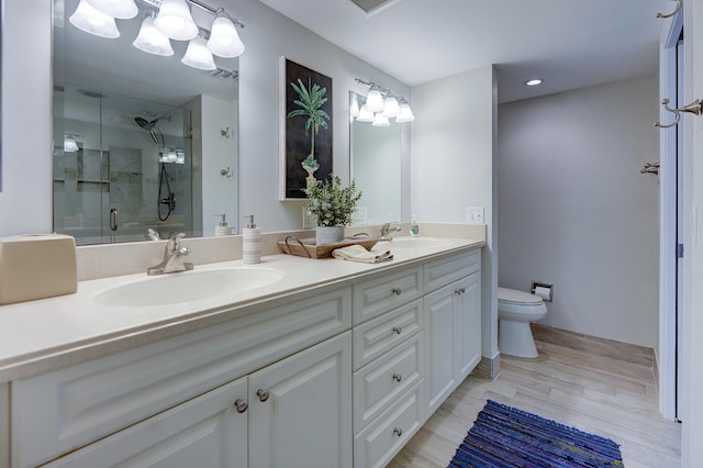 bathroom with a shower with door, large vanity, toilet, and double sink