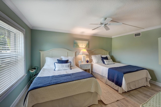 bedroom with wood-type flooring, a textured ceiling, ceiling fan, and crown molding