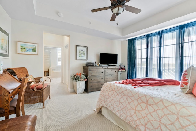 bedroom with multiple windows, light colored carpet, ceiling fan, and ensuite bath