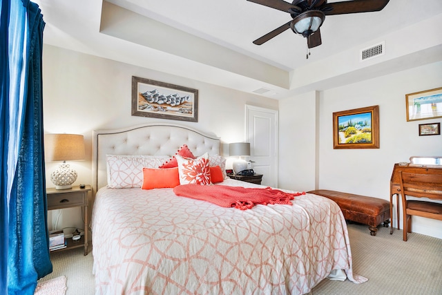 bedroom with light carpet, a raised ceiling, and ceiling fan