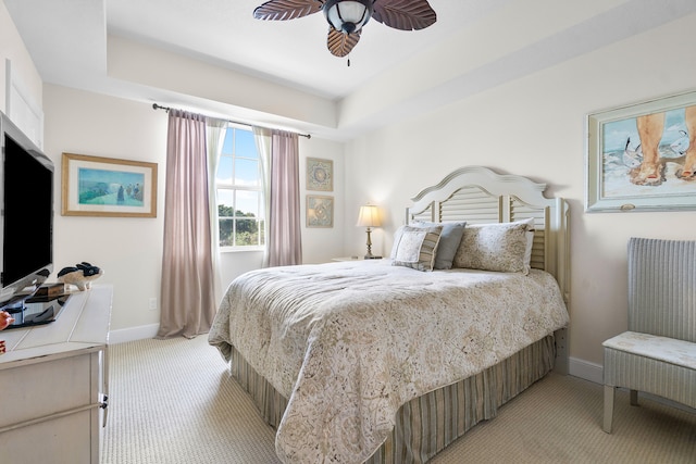 carpeted bedroom with a raised ceiling and ceiling fan