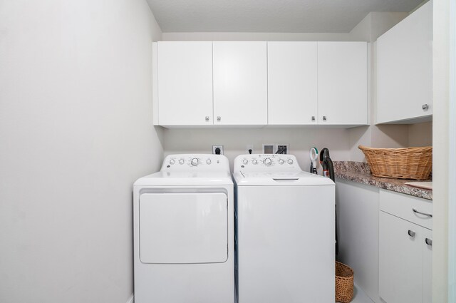 washroom with cabinets and washing machine and clothes dryer