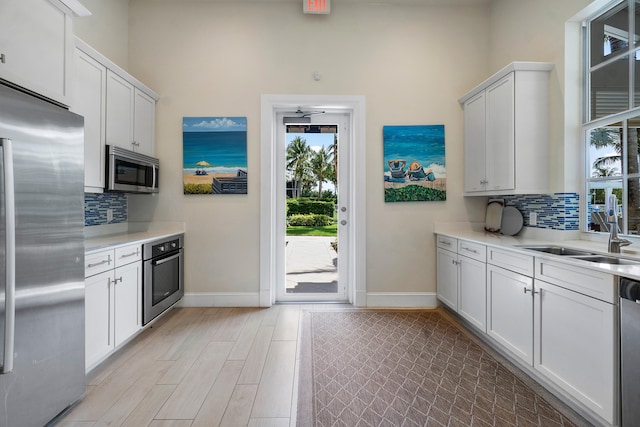 kitchen featuring sink, appliances with stainless steel finishes, white cabinetry, a water view, and decorative backsplash