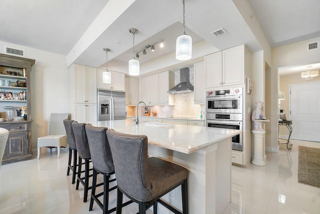 kitchen with sink, white cabinetry, stainless steel appliances, decorative backsplash, and wall chimney range hood