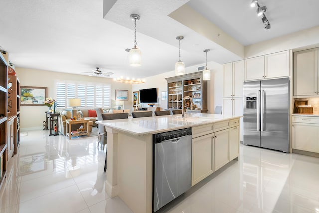 kitchen featuring sink, ceiling fan, appliances with stainless steel finishes, hanging light fixtures, and light stone countertops