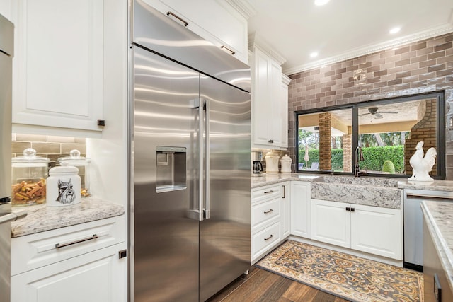 kitchen featuring stainless steel appliances, white cabinetry, and backsplash