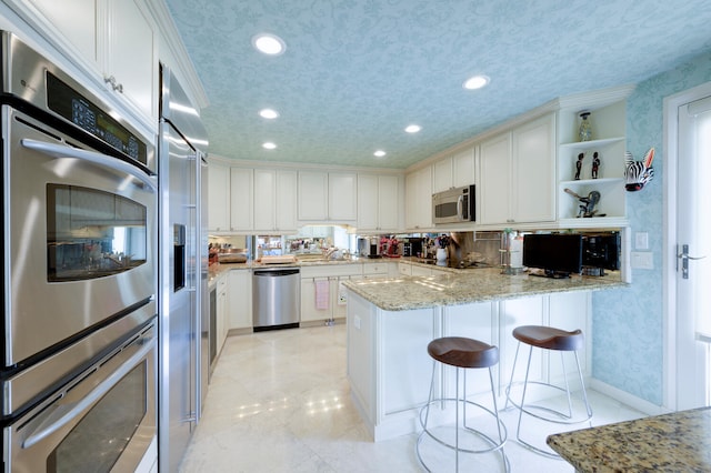 kitchen with white cabinets, a textured ceiling, stainless steel appliances, and kitchen peninsula