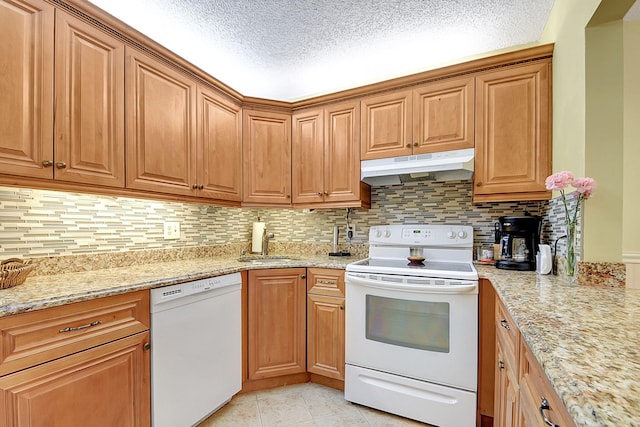 kitchen featuring tasteful backsplash, white appliances, a textured ceiling, and light stone countertops