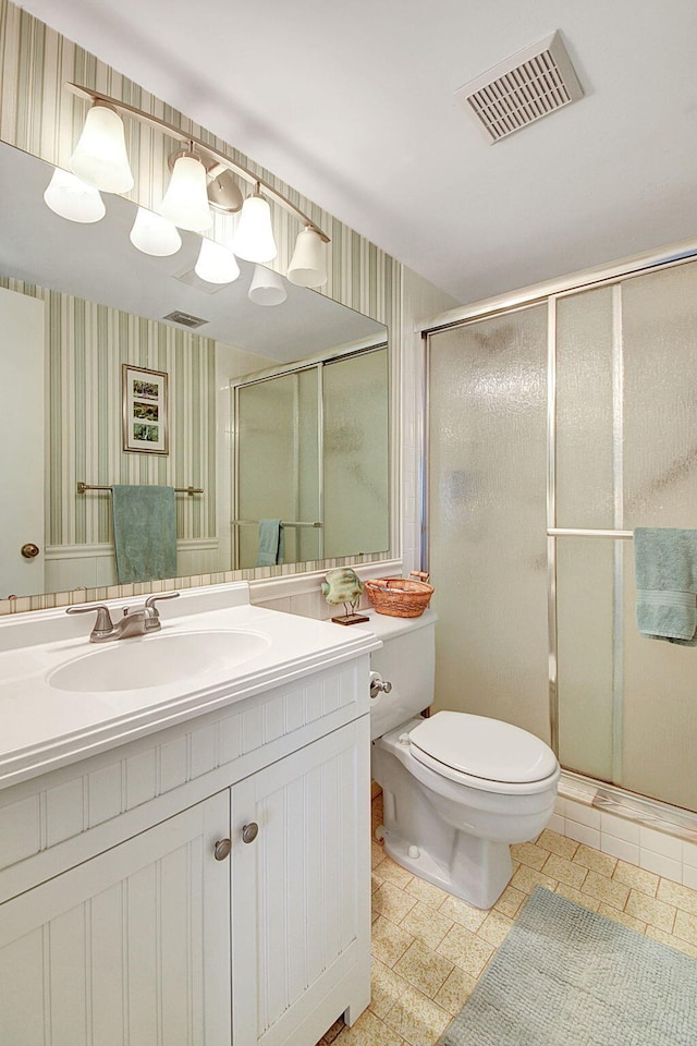 bathroom featuring an enclosed shower, vanity, toilet, and tile flooring