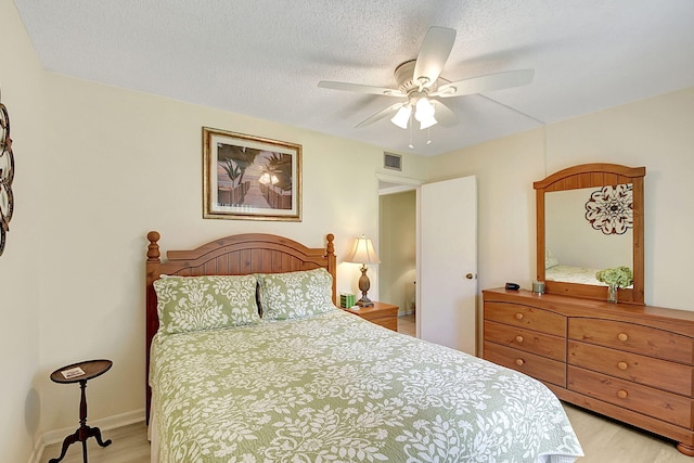 bedroom featuring light hardwood / wood-style flooring, ceiling fan, and a textured ceiling