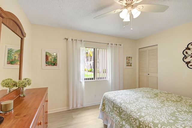 bedroom with a closet, a textured ceiling, ceiling fan, and light hardwood / wood-style floors