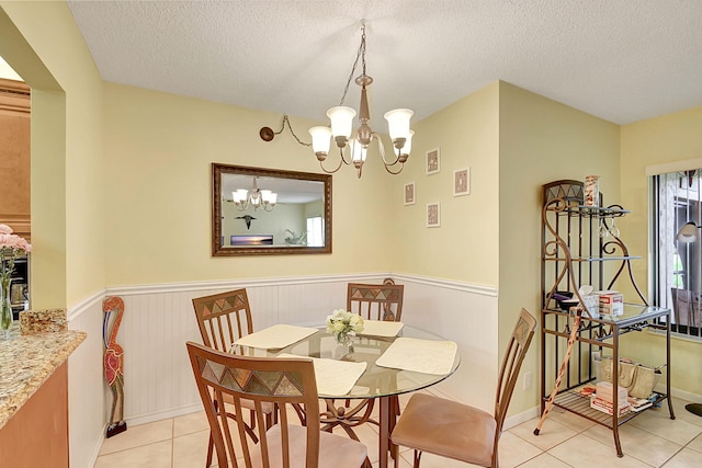 dining space featuring an inviting chandelier, a textured ceiling, and light tile floors