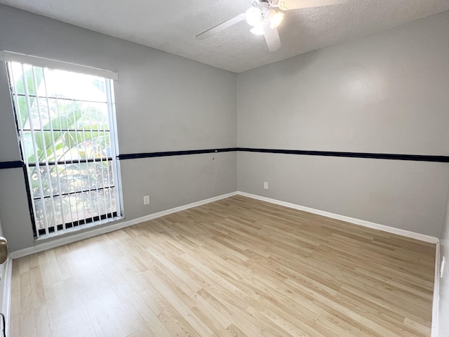 empty room featuring ceiling fan, light wood-type flooring, and a textured ceiling