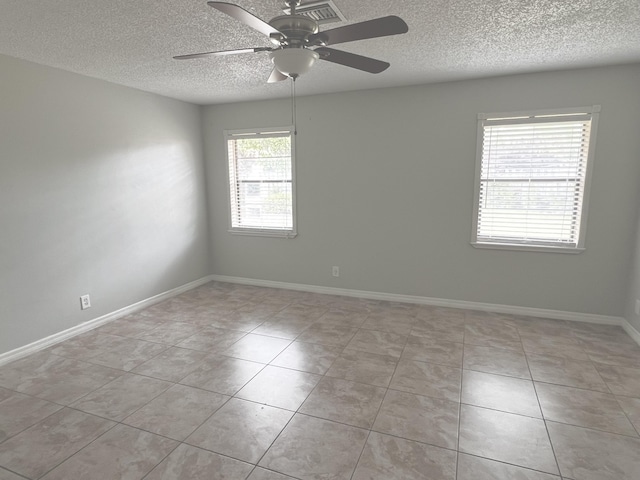 spare room featuring a textured ceiling, ceiling fan, and light tile patterned flooring