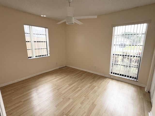 empty room with plenty of natural light, ceiling fan, a textured ceiling, and light hardwood / wood-style flooring