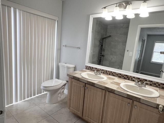 bathroom with tile patterned flooring, vanity, tiled shower, and toilet