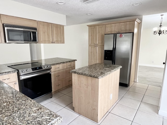 kitchen with a center island, an inviting chandelier, light tile patterned floors, a textured ceiling, and appliances with stainless steel finishes