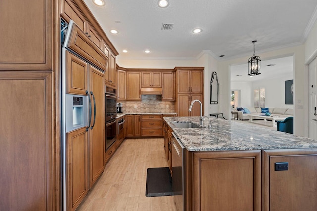 kitchen with a center island with sink, sink, light wood-type flooring, and crown molding