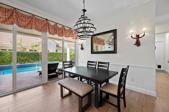 dining space featuring crown molding, light hardwood / wood-style floors, and a chandelier