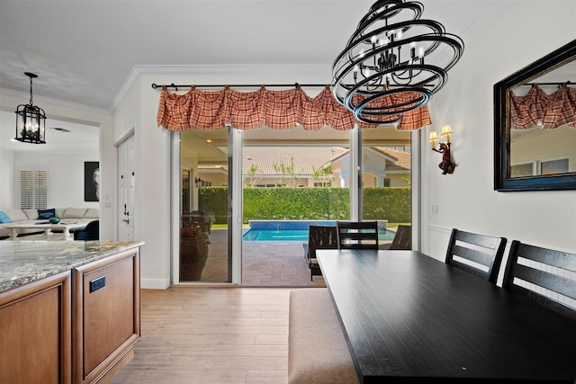 dining area with crown molding, a notable chandelier, and light hardwood / wood-style floors